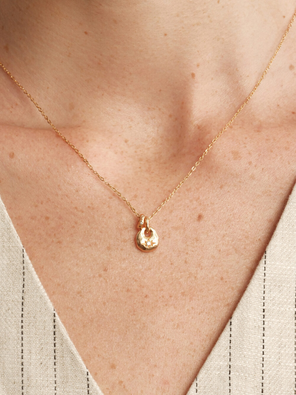 lucky purse n✨ a blessing carried in a tiny purse. the lucky purse necklace draws inspiration from ancient embroidered sachets—symbols of peace, joy, and prosperity. its petite size magnifies its meaning: a vessel that condenses blessings into a precious charm for daily wear. handcrafted with a softly rounded silhouette and a vintage gold finish, the purse motif glows with warmth. at its center lies a delicate starburst engraving, inlaid with a sparkling cubic zirconia that shines like a hidden treasure. every glance reveals its dual essence—ornamental beauty and symbolic protection. whether worn close to the heart or given as a meaningful gift, this necklace brings quiet elegance and timeless good fortune into everyday life. design details miniature purse motif (9mm): inspired by traditional silk sachets, reimagined as a refined jewelry keepsake. starburst engraving: a classic six point carving that enhances the vintage charm. cubic zirconia accent: a luminous centerpiece symbolizing prosperity and joy. dual charms: the purse pendant pairs with a rotating ring detail, balancing “hold & release” in harmony. materials metal: 925 sterling silver with 18k gold plating stone: high grade cubic zirconia (synthetic) finish: hand polished with antique texture dimensions pendant size: 0.37 in x 0.35 in (9.6 mm x 8.8 mm) chain length: 15.7 in (400 mm) + 2.0 in (50 mm) extender weight: approx. 3.2 g styling tips wear as a subtle daily talisman to invite blessings and peace. perfect for layering with delicate chains for a modern, effortless look. a thoughtful gift for birthdays, milestones, or festive occasions—symbolizing good fortune and heartfelt wishes. why you’ll love it 🌟 a timeless symbol of blessings and prosperity 💫 petite yet powerful—small details with deep meaning 🎁 perfect as both a personal keepsake and a meaningful gift ✨ vintage finish and starburst engraving add artisanal charmecklace